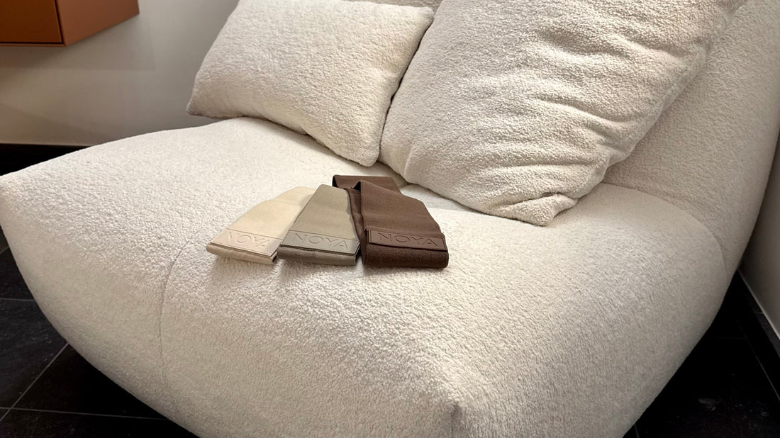 NOYA Resistance Trio — three aesthetic fabric hip bands in natural tones resting on a soft cream armchair, minimalist home gym accessories for mindful movement and bodyweight training.